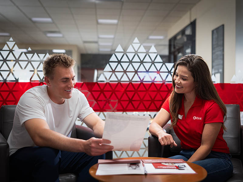 Image of the interior of an Ent Credit Union service center with Denver Broncos quarterback Bo Nix sitting at a table beside an Ent Credit Union mortgage loan expert.
