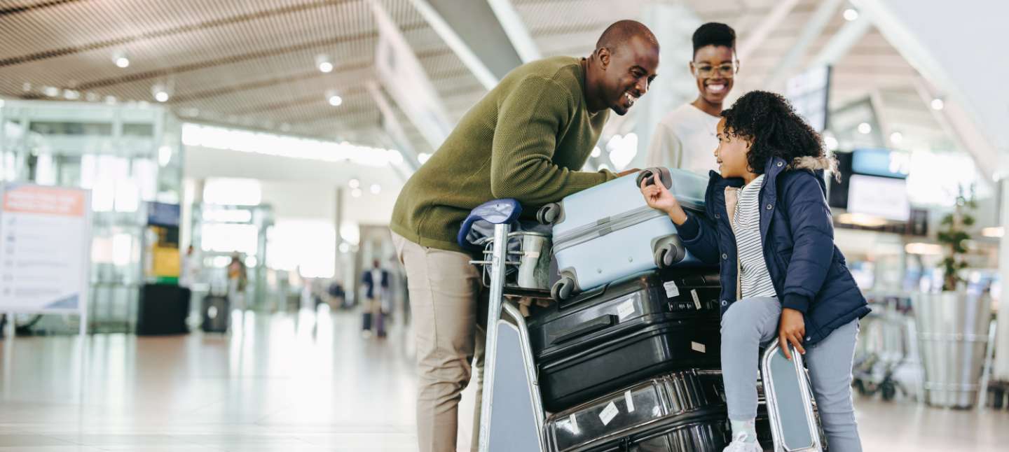 Father and mother waiting with young daughter at airport. Tourist family at airport terminal with luggage holiday.