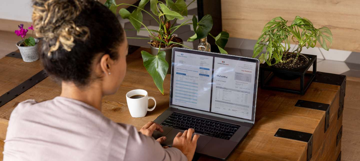 Woman at home checking her bank statements online using a laptop computer.