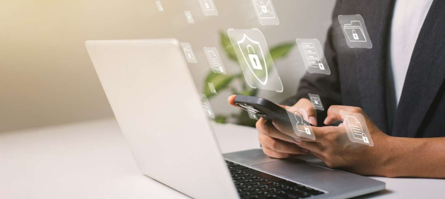 A businessman works on his laptop at home with a virtual display showing a symbol to signify cyber security privacy and online data protection