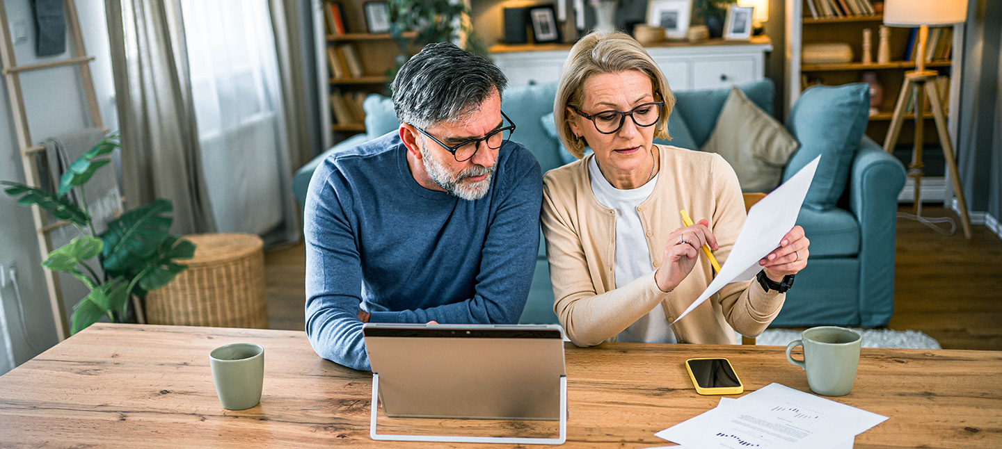 Mature couple manages using a tablet, pen and paper