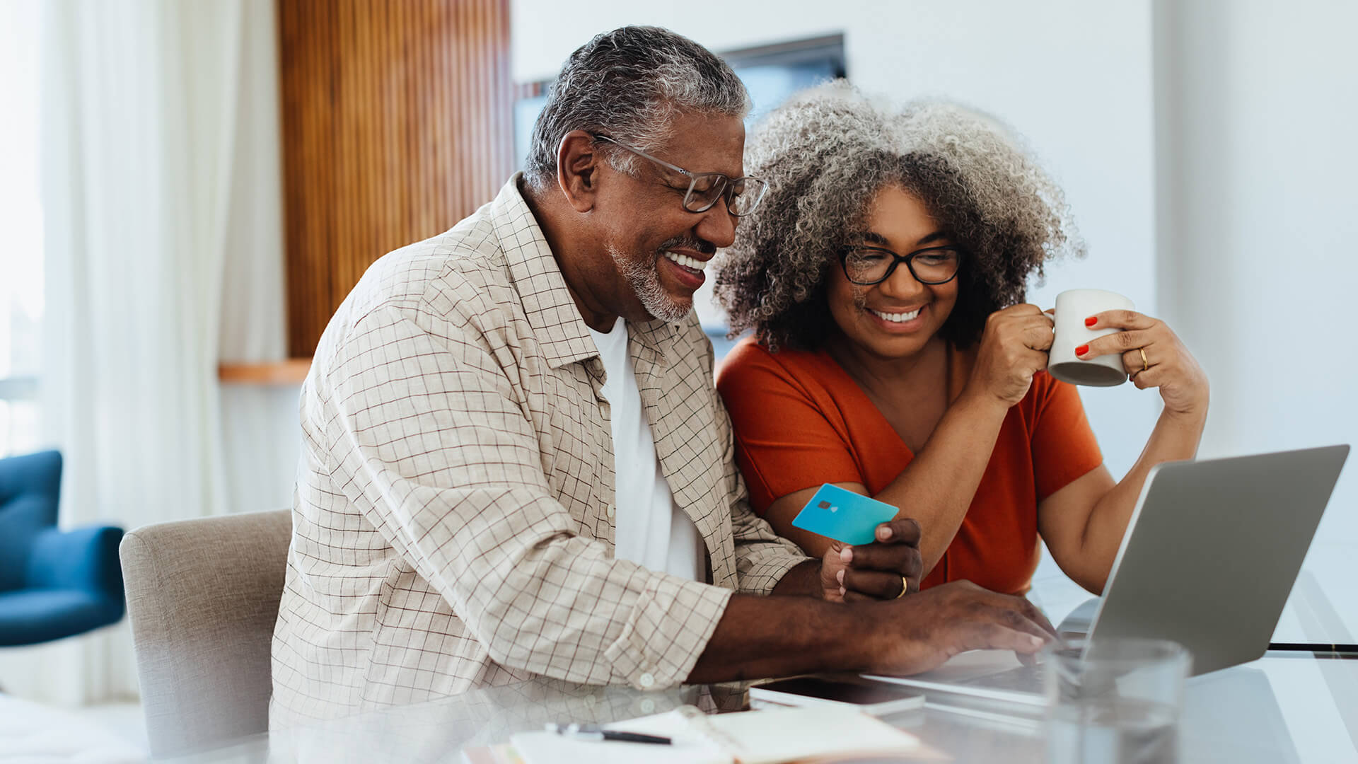 Mature couple doing online banking together, smiling and enjoying their time